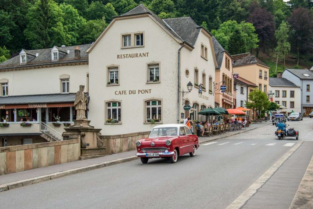 Classic red car driving over the bridge in Vianden next to Café-Restaurant Du Pont, photo by Marcel de Hoog.