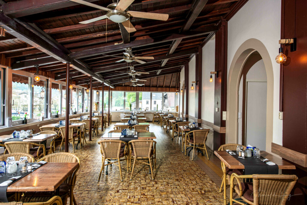 Spacious interior of the Du Pont restaurant in Vianden, with windows on the right overlooking the river Our, photo by Marcel de Hoog.